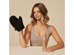 Young woman demonstrating a black Tanning Mitt | NUDA with a bottle of tanning product on a beige background, highlighting skincare and body care application.
