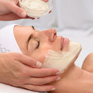 A person receiving a soothing facial treatment with a creamy mask being applied to their cheek, showcasing skincare with Power Lift | HydroPeptide.