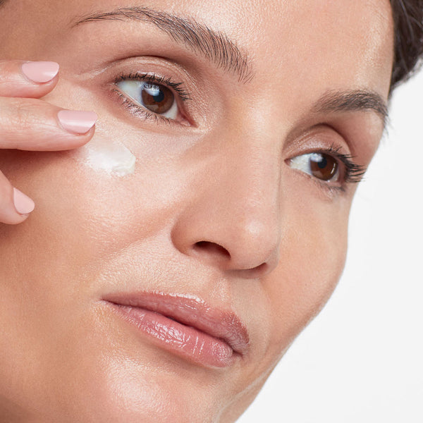 Close-up of a woman gently applying Eye Authority | HydroPeptide skincare cream near her eye, highlighting radiant skin and wellness.