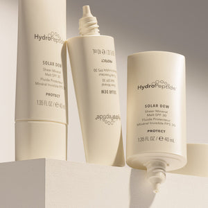Three beige tubes of Solar Dew SPF Mineral Serum | HydroPeptide displayed on a light surface with minimalist branding and clean design, emphasizing skincare and sun protection.