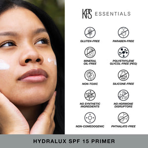Woman applying Hydralux SPF 15 Primer | Kindness Powered Skincare with visible icons highlighting the product’s gluten-free, paraben-free, mineral oil-free, PEG-free, non-toxic, silicone-free, no synthetic ingredients, no hormone disruptors, non-comedogenic, and phthalate-free qualities.