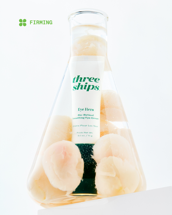 EyeHero™ Bio-Retinol Smoothing Eye Cream | Three Ships tube surrounded by peaches in a clear laboratory flask, emphasizing firming skincare benefits.