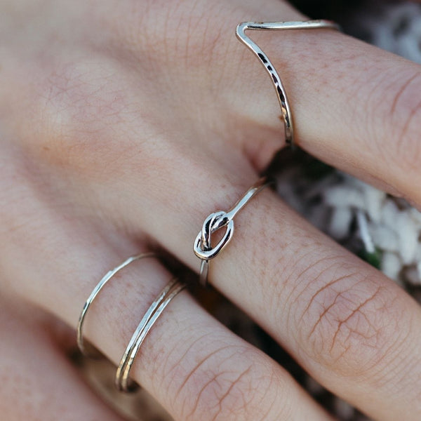 Close-up of a hand wearing delicate silver rings, featuring a knotted design, highlighting the Journey Ring | Purpose Jewelry with a minimalist and elegant style.