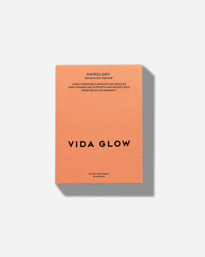Orange box packaging for Hairology Capsules | VIDA GLOW dietary supplement with text describing it as a daily capsule to reduce hair thinning and support hair growth.