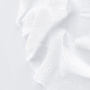 Close-up of the textured white sheet material from the Oligoforce Lumination Targeted Dark Spot and Wrinkle Sheet Mask With Vitamin B3 - 4 Mask Set| Phytomer, highlighting its smooth, hydrating skincare fabric.