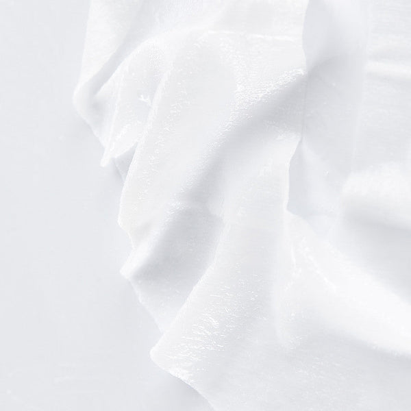 Close-up of the textured white sheet material from the Oligoforce Lumination Targeted Dark Spot and Wrinkle Sheet Mask With Vitamin B3 - 4 Mask Set| Phytomer, highlighting its smooth, hydrating skincare fabric.