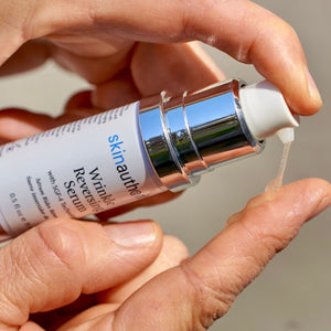 Hands dispensing a clear serum from a pump bottle labeled Complete Serum | Skin Authority, highlighting skincare application and wellness routine.