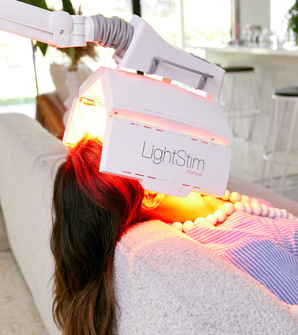 Woman receiving red light therapy treatment on her face from a LightStim ProPanel | LightStim device in a bright, modern setting focused on skincare and wellness.