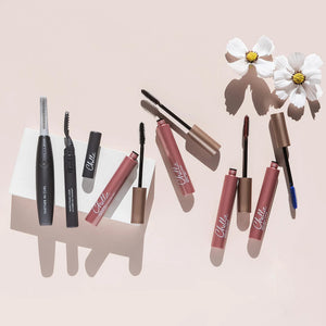 Deluxe Heated Eyelash Curler | Chella displayed alongside mascara tubes and applicators on a light background with white flowers, highlighting beauty and wellness tools.