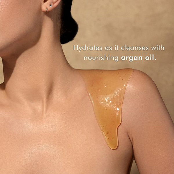 Close-up of a woman with golden shower gel dripping down her shoulder, showcasing the hydrating and nourishing properties of Shower Gel | Moroccanoil with argan oil for skincare.