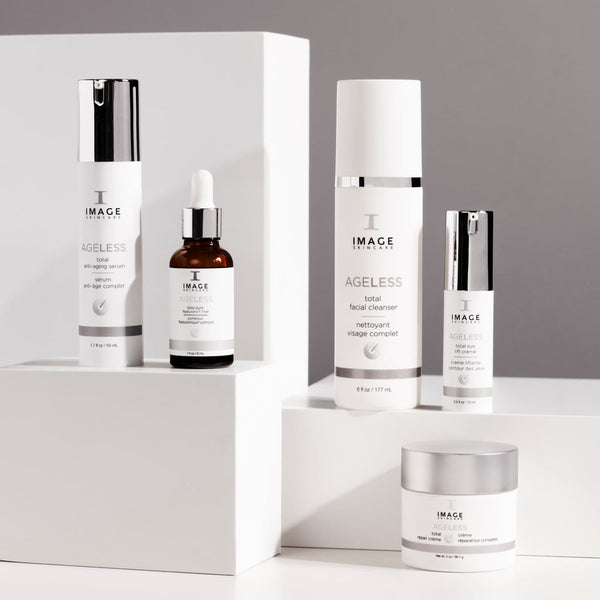 Collection of AGELESS total pure hyaluronic 6 filler | IMAGE Skincare products including serum, facial cleanser, and moisturizing cream displayed on white geometric platforms for skincare wellness.
