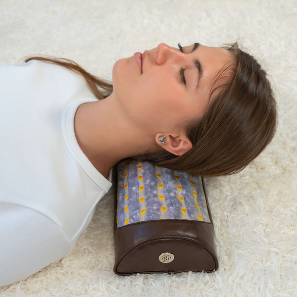 Woman resting her head on an amethyst bolster pillow with a brown leather base, demonstrating relaxation and comfort using the Amethyst Bolster Firm - Heated InfraMat Pro® | HealthyLine for wellness and recovery.
