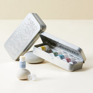 Wellbeing Ritual Aromatherapy Mini Tin | Scentered featuring a sleek silver tin with five small aromatherapy balms in various colors, designed for wellness and body care rituals.