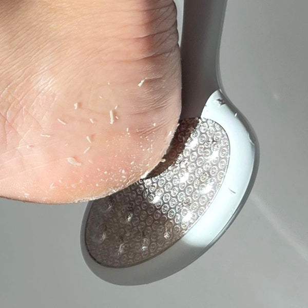 Close-up of a foot being exfoliated with a metallic foot file, demonstrating skin smoothing and care using the Smooth Things Over | Barefoot Scientist wellness device.