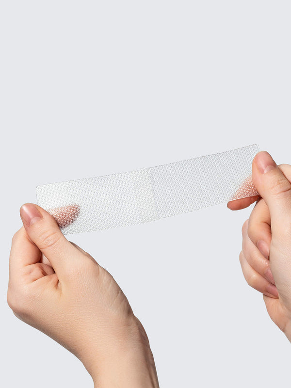 Hands holding a transparent, breathable patch designed for skin recovery featuring SiliconeFusion™ C-Section Patch | Dermaclara for gentle post-surgery care.