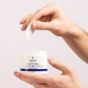 Hands holding a jar and a pad of CLEAR CELL salicylic clarifying pads | IMAGE Skincare, designed for skincare and skin clarity with salicylic acid.