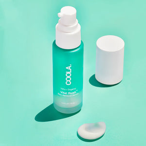 Bottle of Vital Rush™ Skin Renewal Serum | COOLA with the white pump cap removed and a dollop of serum on a turquoise surface, highlighting skincare product quality.