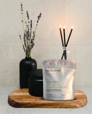 Charcoal Garden Detox Crush | Bathorium pouch displayed on a wooden tray with black vessels lavender stems and lit incense in a calm spa setting