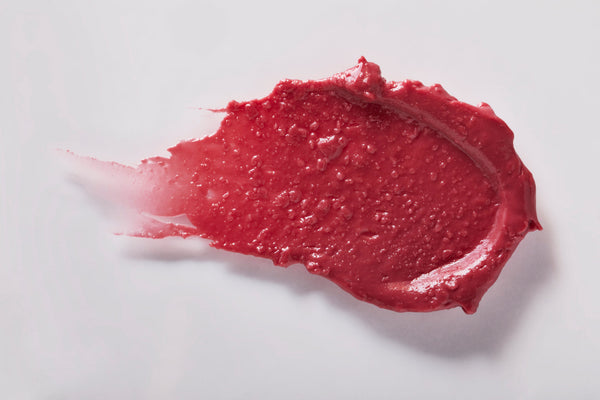 Smudged red tinted lip balm texture representing Classic Liplux® Lip Balm Tinted SPF 30 | COOLA for glossy, sun-protective skincare.