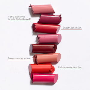Seven broken lipstick pieces in various shades from nude to deep red are arranged vertically with text describing features including highly pigmented color, smooth satin finish, creamy no-tug texture, and rich yet weightless feel featuring ColorLuxe Hydrating Cream Lipstick | Jane Iredale.