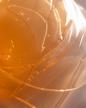 Close-up of translucent orange gel texture with small bubbles, representing skincare ingredients for Brighter Days Red Algae + Avocado Biodegradable Eye Masks | Three Ships.