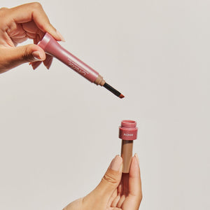 Hands holding an eyebrow cream applicator and matching container in a warm blonde shade for precise brow grooming featuring Eyebrow Cream | Chella.