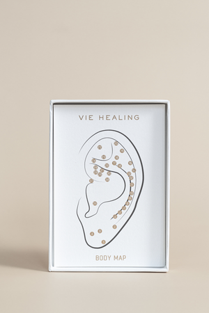 The Foundation - 24K Gold Ear Seed | Vie Healing packaging displaying a minimalist ear body map illustration with numbered points, designed for wellness and recovery.