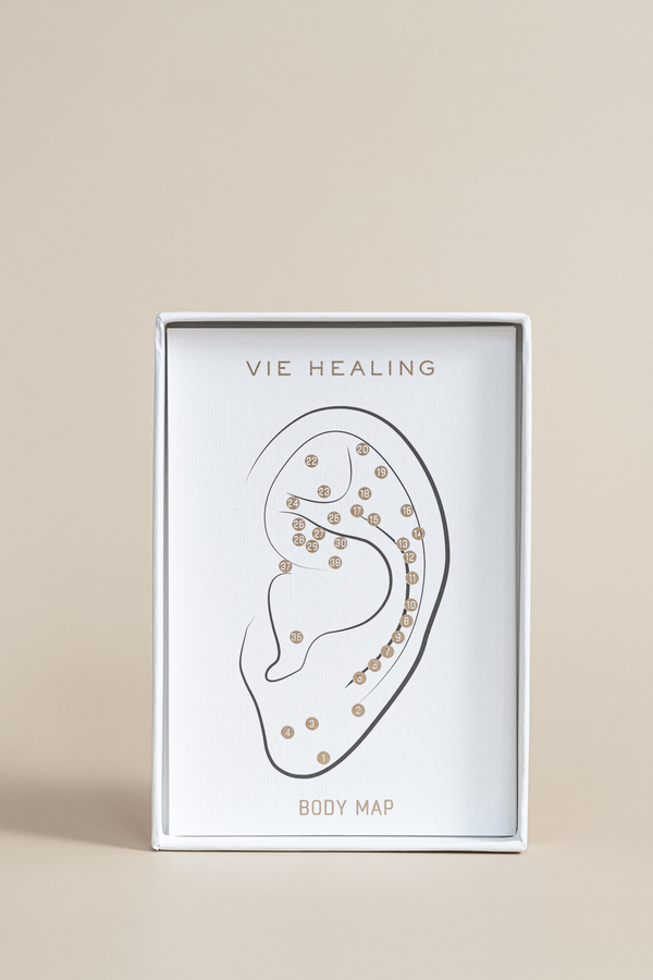 The Foundation - 24K Gold Ear Seed | Vie Healing packaging displaying a minimalist ear body map illustration with numbered points, designed for wellness and recovery.