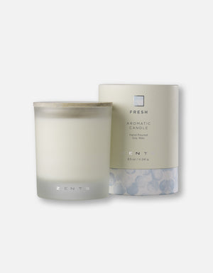 A hand-poured soy wax Aromatic Candle | Zents in a frosted glass container with a wooden lid, displayed next to its elegant packaging labeled Fresh for a calming wellness experience.
