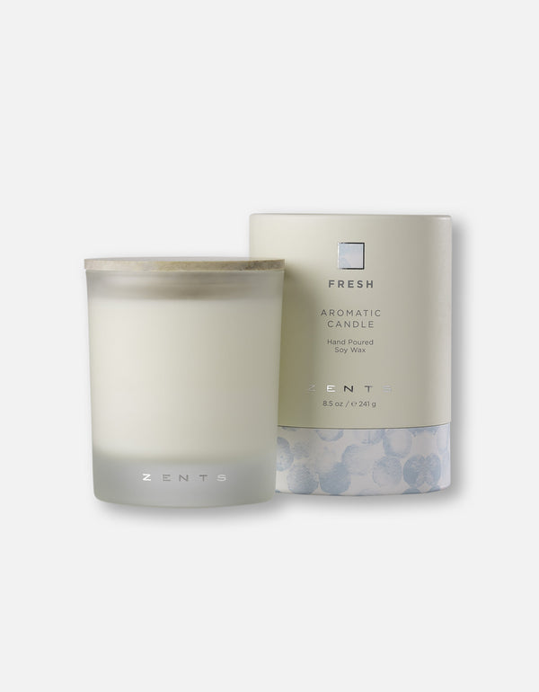 A hand-poured soy wax Aromatic Candle | Zents in a frosted glass container with a wooden lid, displayed next to its elegant packaging labeled Fresh for a calming wellness experience.