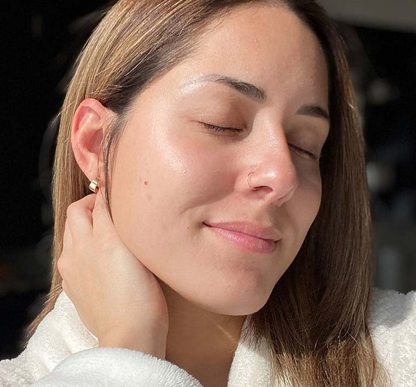 Close-up of a woman with glowing skin and closed eyes, showcasing natural radiance and smooth texture after using Full Moon Dip® Iridescent Illumination Ageless Facial Mousse with Peptides + Retinol | Farmhouse Fresh skincare product.