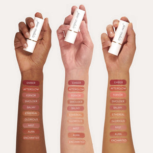 Three diverse hands each holding a Glow Time Blush Stick | Jane Iredale with multiple blush shades swatched on their arms showing color range and finish.