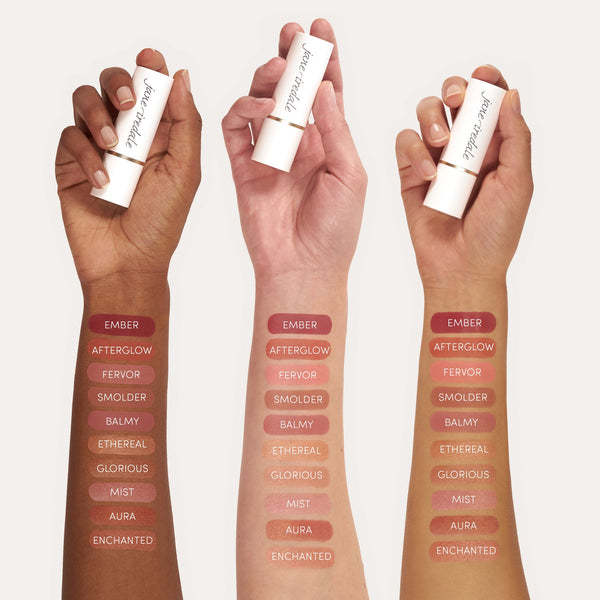 Three diverse hands each holding a Glow Time Blush Stick | Jane Iredale with multiple blush shades swatched on their arms showing color range and finish.