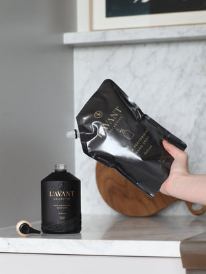 Refilling a sleek black hand soap bottle with High Performing Hand Soap Refills | L'AVANT Collective for a luxurious skincare and body care experience.