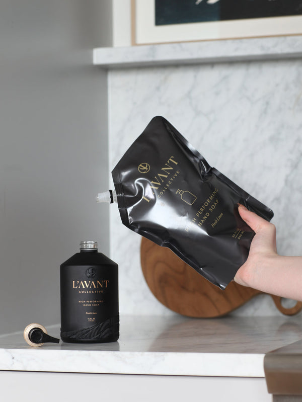 Refilling a sleek black hand soap bottle with High Performing Hand Soap Refills | L'AVANT Collective for a luxurious skincare and body care experience.