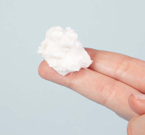 A close-up of a hand holding a small amount of white creamy texture representing Harvest Moon Dip® | FarmhouseFresh skincare product on fingertips.