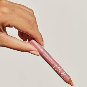 Hand holding a pink Highlighter Pencil | Chella against a neutral background, highlighting its smooth texture and precise tip for skincare makeup application.