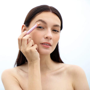 Woman applying makeup with Highlighter Pencil | Chella on her eyebrow area, demonstrating a natural skincare and beauty routine.