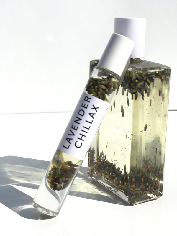 Clear glass bottles filled with liquid and suspended lavender buds, featuring the Lavender Chillax Organic Perfume Roll-on | Hydra Bloom in a sleek rollerball design ideal for wellness and body care.
