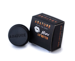 Small black container and box of Abature Mini | Abature lip butter with orange and white text, designed for skincare and lip care.
