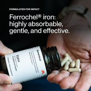 Close-up of hands holding an open bottle of Iron+ dietary supplement with capsules being poured into the palm, highlighting the product's formulation for gentle, highly absorbable iron.