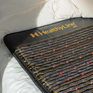 Jet Series - PEMF Far Infrared Heating Mats | HealthyLine laid out on a bed with visible red therapy points and textured stitching, promoting wellness and recovery.