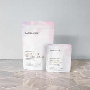 Midnight Superbloom Crush | Bathorium pink and white bath soak pouches displayed on a light hexagonal tile surface against a soft gray background