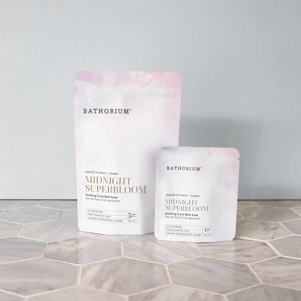 Midnight Superbloom Crush | Bathorium pink and white bath soak pouches displayed on a light hexagonal tile surface against a soft gray background