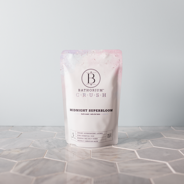 Midnight Superbloom Crush | Bathorium packaging standing on a geometric tile surface, featuring a soft pink and white design for a skincare bath soak product.
