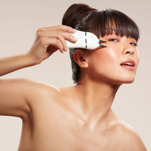 Woman using the TRINITY+ Effective Lip & Eye Attachment | NuFACE facial device near her eye, demonstrating skincare and wellness care with a sleek white tool.