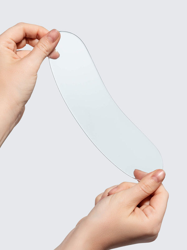 Hands holding a clear, flexible silicone patch designed for skincare, showcasing the SiliconeFusion™ Neck Patch | Dermaclara for wrinkle reduction and body care.