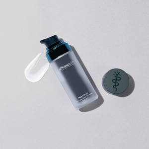 Bottle of Night Serum | Althaea Skin with a swirl of white serum next to a round cap featuring a medical symbol, displayed on a light gray surface for skincare and wellness.
