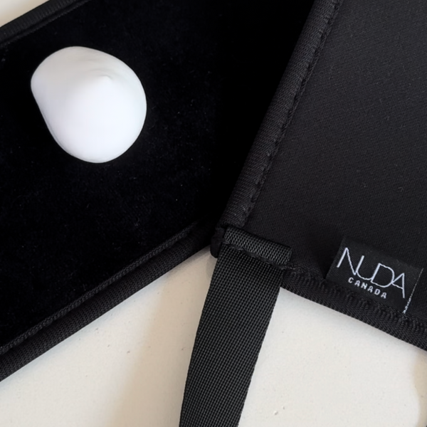 Close-up of a black fabric Self Tan Back Applicator | NUDA with a black strap and white cream on a black surface, designed for even self-tanning application on the back.