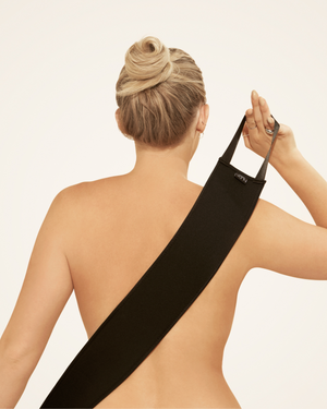 Person with hair in a bun using the black Self Tan Back Applicator | NUDA to evenly apply self-tanner to their back for smooth and easy skincare application.
